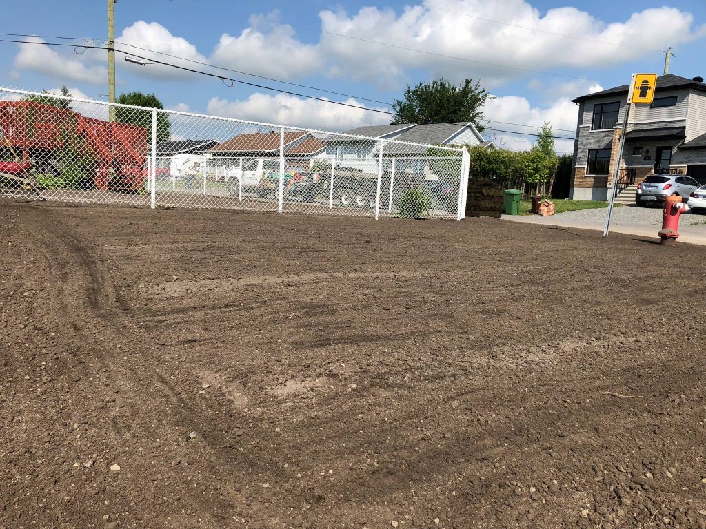 Topsoil soigneusement raclé et étalé, préparant le terrain pour un ensemencement efficace ou l'installation de tourbe.