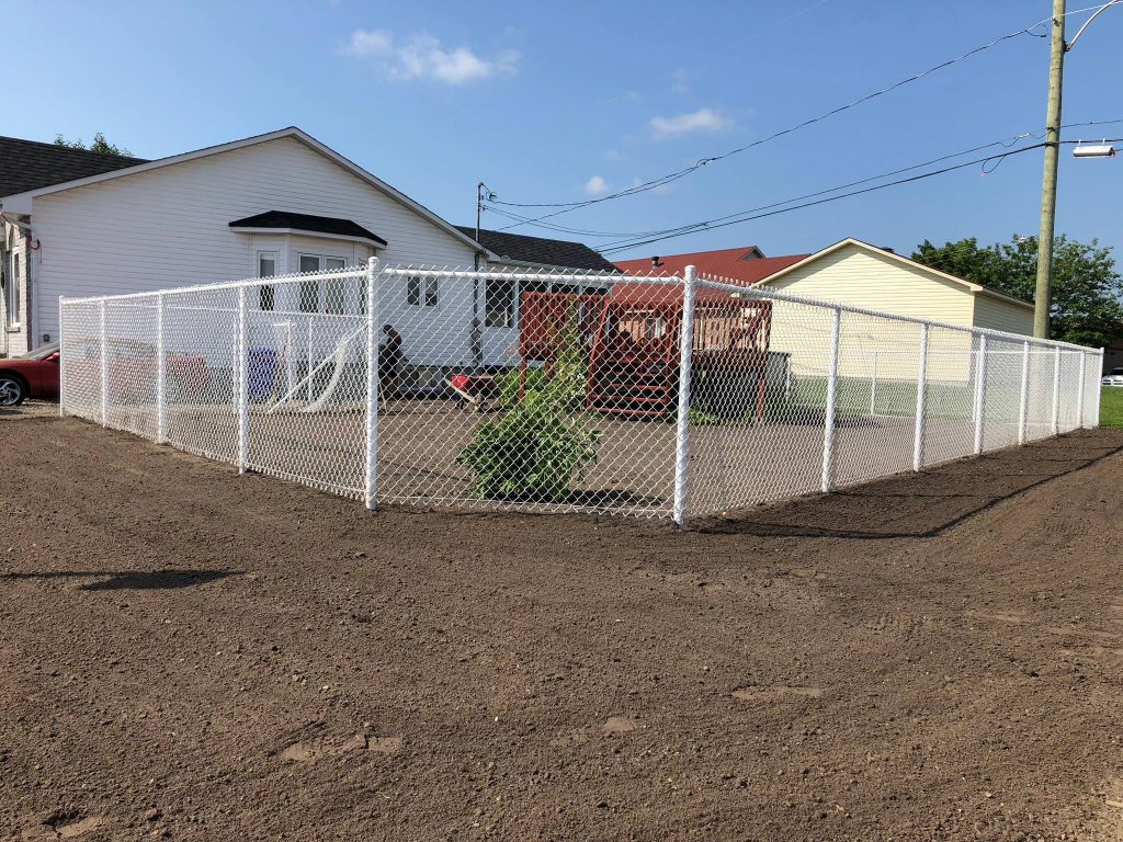 Terre enrichie en topsoil, raclée et étendue, préparant idéalement le sol pour ensemencement ou pose de tourbe.